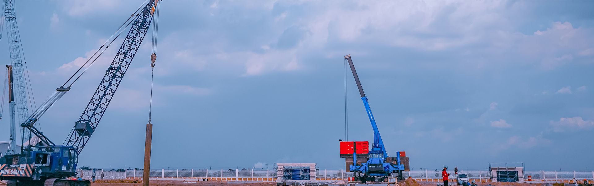 Cranes lifting piles on open site